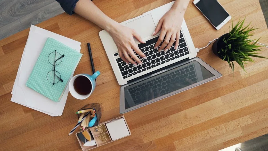 A modern workspace showing hands analyzing marketing data on a laptop and paper documents.